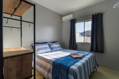 a small bedroom with a bed and a window at Curta Praia de Armação - Casa Coqueiro in Penha