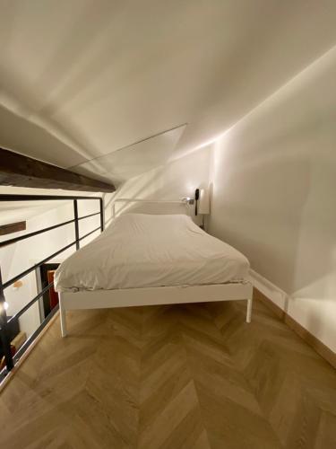 Cama blanca en habitación con suelo de madera en Hôtel Média en París