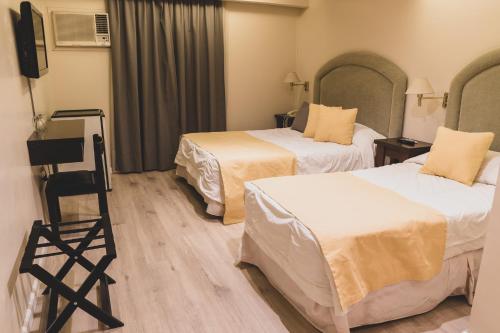 a hotel room with two beds and a television at Hotel Metropol in San Miguel de Tucumán
