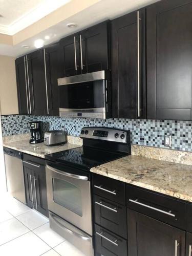 a kitchen with stainless steel appliances and black cabinets at Stylish Home close to everything in Hollywood