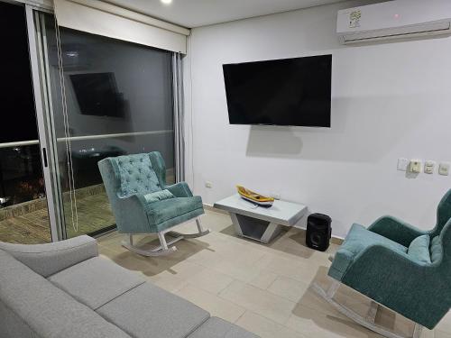 a living room with a couch and two chairs and a flat screen tv at Yellow beach & rest II in Coveñas