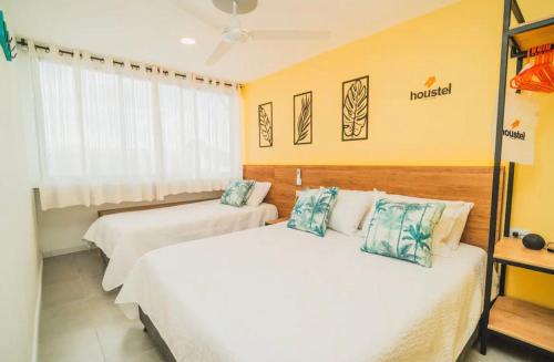 two beds in a room with yellow walls at Bocagrande Houstel Ctc Medium in Cartagena de Indias
