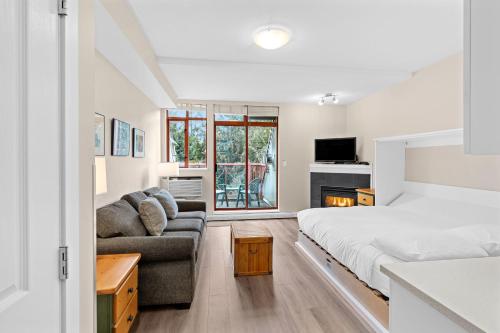 a bedroom with a bed and a couch at Alpenglow Lodge Studio with park view by MVA in Whistler