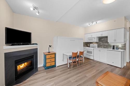 a living room with a fireplace and a table with chairs at Alpenglow Lodge Studio with park view by MVA in Whistler