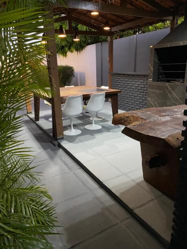 a patio with a wooden table and two white chairs at Casa em Piranhas AL - Alto Padrão in Piranhas