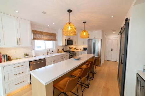 a kitchen with white cabinets and a large island with bar stools at Harbor Lookout - Luxury Beach Home with Coastal Views - Walk to everything! in Newport Beach