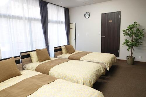 a hotel room with three beds and a clock on the wall at THE TORII - Vacation STAY 21195v in Kumamoto