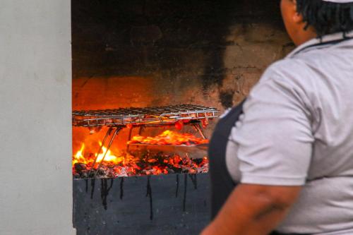 a man is cooking food on a grill at Barefoot Addo Elephant Lodge in Addo