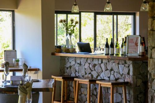 a bar with bottles of wine and windows at Barefoot Addo Elephant Lodge in Addo