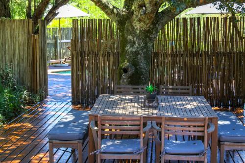a wooden table and chairs under a tree at Barefoot Addo Elephant Lodge in Addo