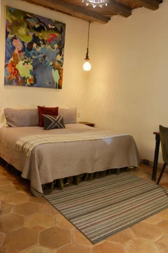 a bed in a room with a painting on the wall at Hotel Amor y Paz in Real de Catorce