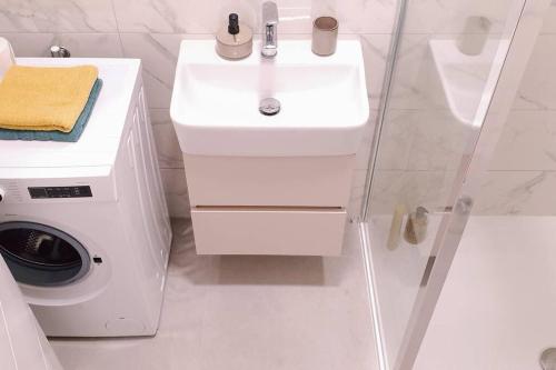 a white bathroom with a sink and a washing machine at R-RESIDENCe in Banja Luka