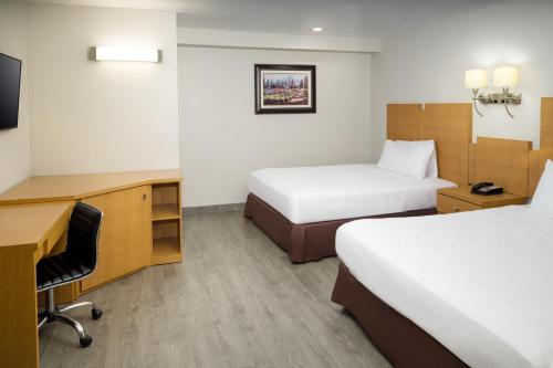 a hotel room with two beds and a desk at Skyview Motel in Fort Lee