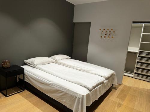 uma cama com lençóis brancos e almofadas num quarto em North Apartment City house. em Tromsø
