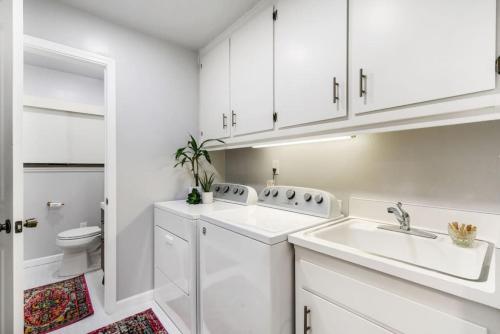 Baño blanco con lavabo y aseo en Mid-Century-Modern Airport Home, en Sacramento