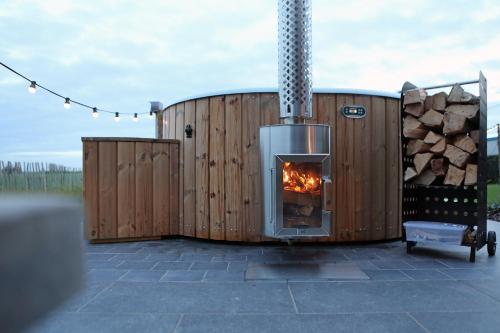 - une cheminée sur une terrasse dotée d'un tas de bois dans l'établissement Florentinus met hottub, afgesloten tuin en overdekt terras, à Furnes