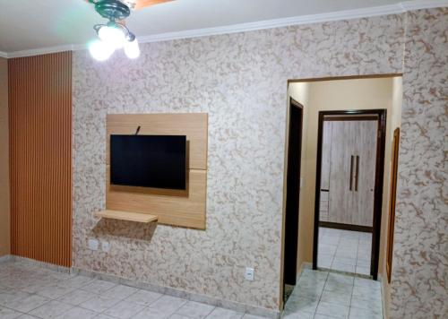 a living room with a television on a wall at Apartamento Praia Grande Aviação in Praia Grande