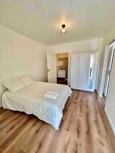 バニョレにあるMagnificent apartment Paris Bagnolet 302のウッドフロアのベッドルーム1室(白いベッド1台付)