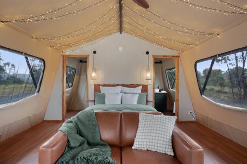 Akuna Estate - Luxury Glamping Experience في Excelsior: غرفة نوم في خيمة مع سرير وأريكة