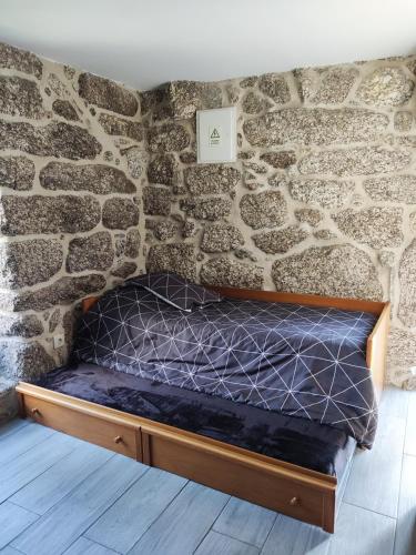 a bed in a room with a stone wall at Cantinho da Pereira in Lugar
