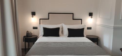 a bedroom with a large bed with black and white pillows at Le Petit Boutique Hotel in Santander