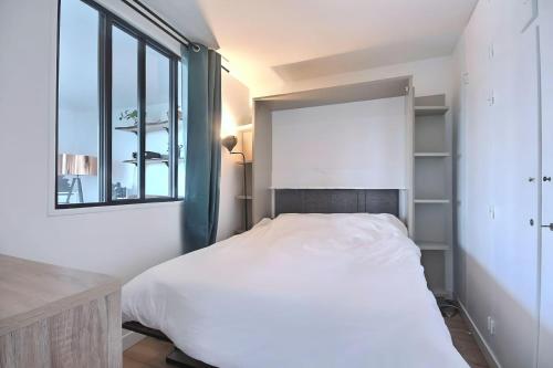 une chambre avec un lit blanc et une fenêtre dans l'établissement Paradis du Canal St-Martin et Jardin Villemin, à Paris