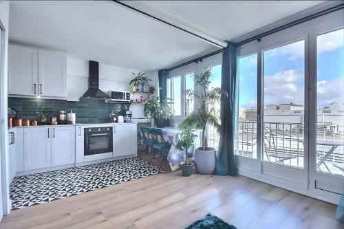 une cuisine avec des placards blancs et une grande fenêtre dans l'établissement Paradis du Canal St-Martin et Jardin Villemin, à Paris