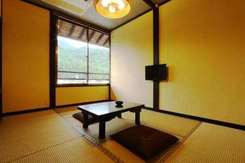 a room with a table in front of a window at Tabinoyado Asonoyu in Aso