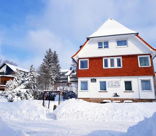 a house is covered in snow in a yard at Hotel Elisabeth Ilse in Braunlage