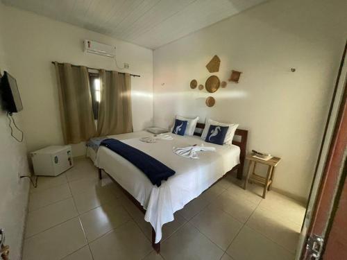a bedroom with a large white bed with blue pillows at Pousada Pura Vida in Barreirinhas