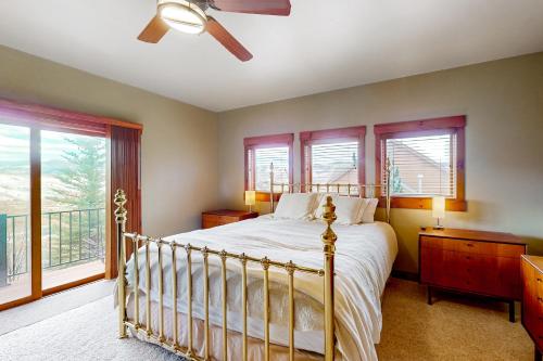 a bedroom with a bed with a ceiling fan and windows at Saddle Ridge Ranch in Granby