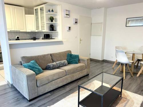a living room with a couch and a table at Cocon Eudenia - accès direct PARIS - 2 MIN RER - PARKING GRATUIT in Cergy