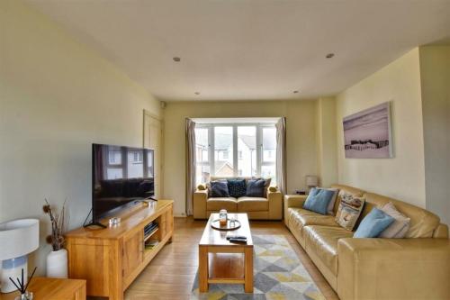 a living room with a couch and a tv at The Beach House, With Secure Garage for Guest Use in Camber