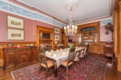 una sala da pranzo con tavolo, sedie e lampadario pendente di Chateau Tivoli Bed and Breakfast a San Francisco