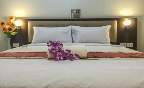 uma cama branca com flores roxas em cima em The Room Mahidol Chiangmai em Chiang Mai