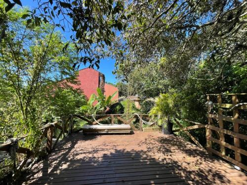 un puente de madera con un banco en un jardín en CASA DE CHICO - Tiny & Suíte, en Guarda do Embaú