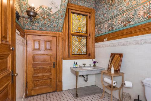 La salle de bains est pourvue d'un lavabo et d'une porte en bois. dans l'établissement Chateau Tivoli Bed and Breakfast, à San Francisco