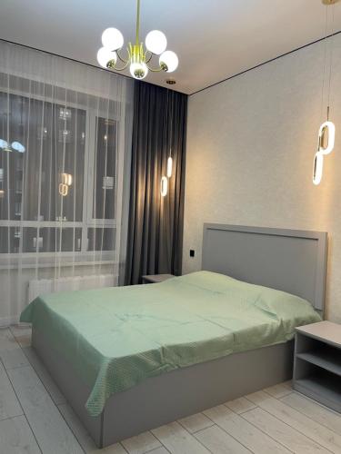 Un dormitorio con una cama verde y una lámpara de araña. en Sharyn, en Kirovo