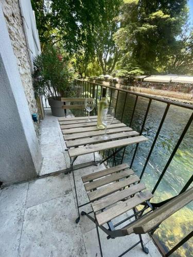 a table and chairs sitting on a balcony next to the water at Riverside flat between Isle sur la Sorgue & Gordes in Fontaine-de-Vaucluse