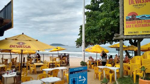 un gruppo di tavoli e ombrelloni su una spiaggia di Studio Morro das Pedras a Florianópolis
