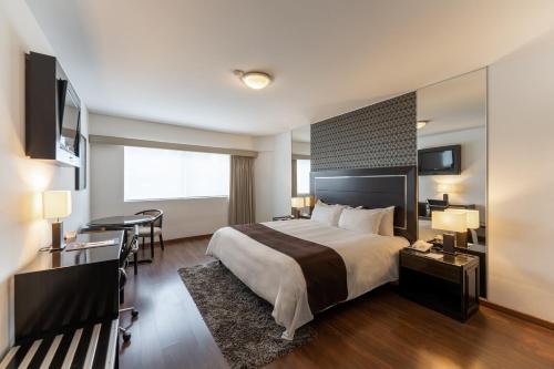 a hotel room with a large bed and a desk at Hotel Jose Antonio in Lima