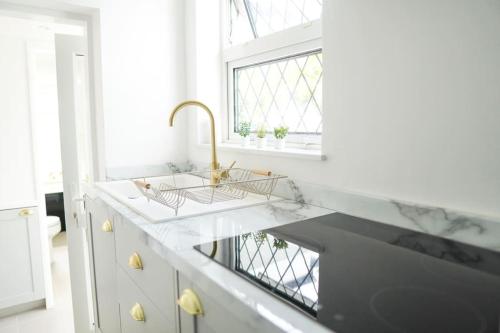 a white kitchen with a sink and a window at Rye Harbour Cosy Cottage in Rye