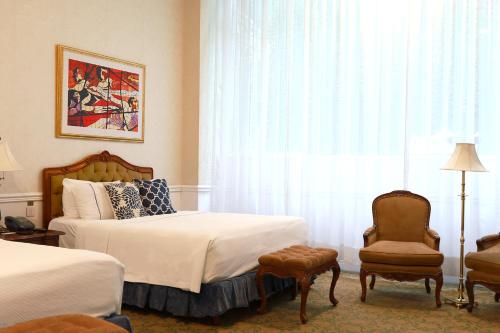 a bedroom with two beds and a chair and a window at Gran Hotel Ciudad de México Zócalo View in Mexico City
