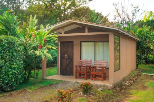 Cabaña pequeña con 2 sillas en el jardín en Slow Travel Lodge, en Upala