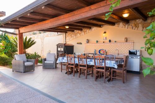 a patio with a table and chairs and a kitchen at Villa Carilù in Altavilla Milicia