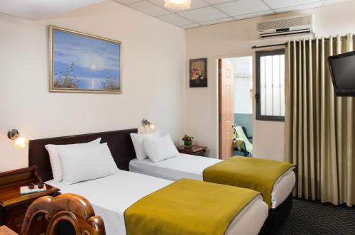 een hotelkamer met 2 bedden en een televisie bij Sun City Hotel in Tel Aviv