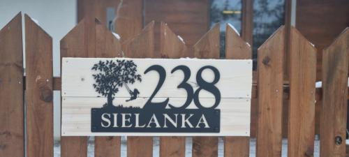 un panneau sur une clôture en bois avec un arbre sur celle-ci dans l'établissement Borsk Sielanka, à Borsk