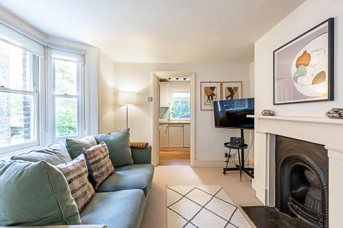 a living room with a blue couch and a fireplace at Cosy Flat in Battersea Park in London