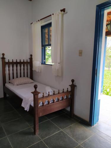 a bed in a room with a window at Pousada Sino dos Ventos in São Sebastião do Rio Verde