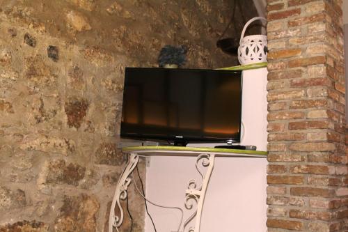 a tv sitting on a stand next to a brick wall at Guest House La Casetta in Piazza Armerina